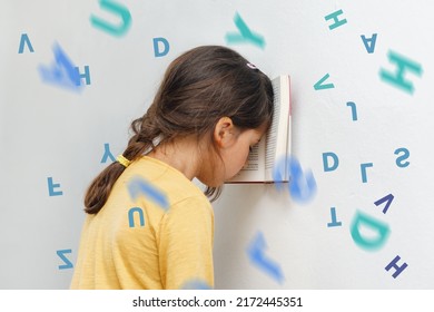Sad and tired caucasian girl with dyslexia holds a book on her forehead. Flying tangled letters in the air. The child learns to speak and read correctly