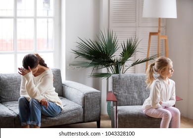Sad tired mother and sulky angry offended child girl not talking after conflict in living room, stubborn kid daughter pouting ignoring depressed mother upset by argument, family conflict concept