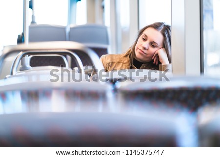 Sad tired woman in train or bus. Bored or unhappy passenger sitting in tram leaning against hand. Upset lady on a late delayed bus. Negative public transportation concept.