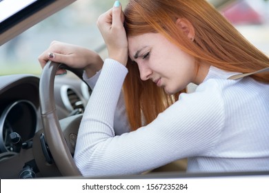 Sad tired yound woman driver sitting behind the car steering wheel in traffic jam.