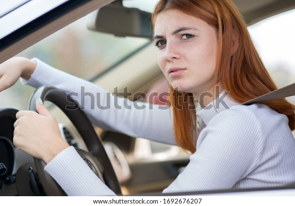 Sad tired yound woman driver sitting behind\
the car steering wheel in traffic\
jam.