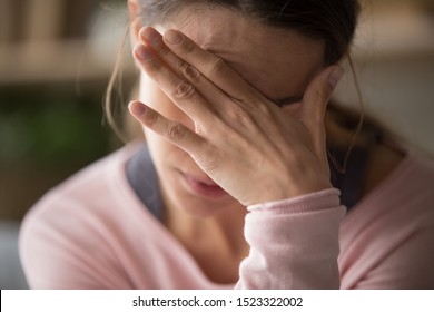 Sad tired young woman touching forehead having headache migraine or depression, upset frustrated girl troubled with problem feel stressed cover crying face with hand suffer from grief sorrow concept