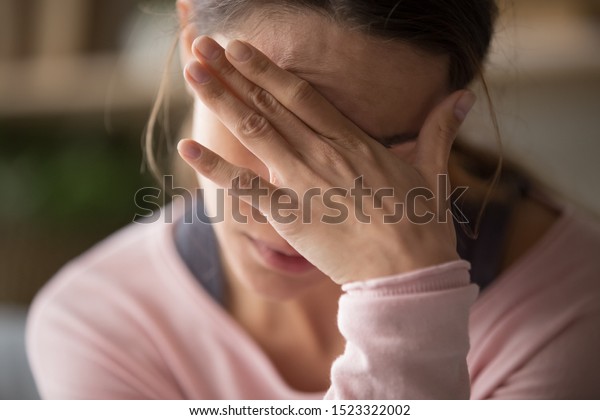 Sad tired young woman touching forehead having
headache migraine or depression, upset frustrated girl troubled
with problem feel stressed cover crying face with hand suffer from
grief sorrow concept