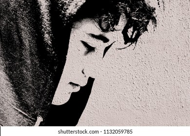 Sad troubled teenager school boy with hood on posing outdoor - stock photo made like graffiti stencil painting on white concrete wall. Close up image.