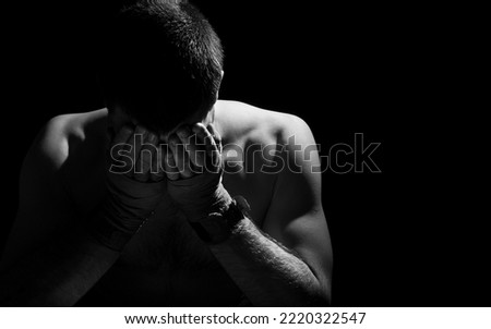 Sad unfortunate athlete. Willingness to win despite defeats. Man holds face with hands wrapped in boxing bandages on black background with space for text. Fighting the habit. Depression