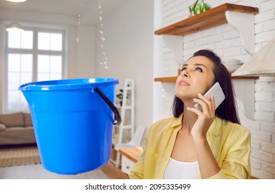 Sad unhappy frustrated young lady speaking to repair service while holding bucket and looking up at water falling down from damaged ceiling in newly renovated kitchen interior. House roof leak concept