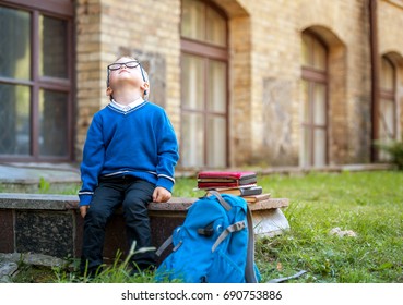 Sad And Unhappy Pupil With Backpack. Upset Toddler Boy. Problem Child. Concept For Bullying, Depression Stress Or Frustration. On School Background. Education For Small Kids.