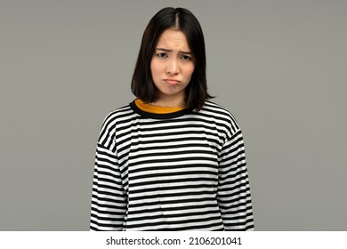 Sad Unhappy Woman Looking At Camera With Pout Lips, Being Upset Of Bad News. Indoor Studio Shot Isolated On Grey Background 