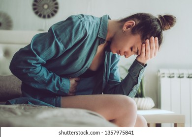 Sad, unhappy woman suffering from PMS and menstruation pain. Having stomach ache, abdominal pain and headache because of critical days. Inflammation and infection bladder, cystitis. Health problems