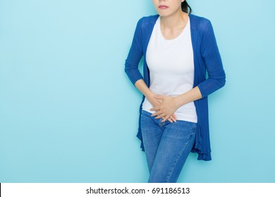 sad unhappy woman using hands touching belly position when she feeling painful suffering during menstruation period isolated on blue background.
