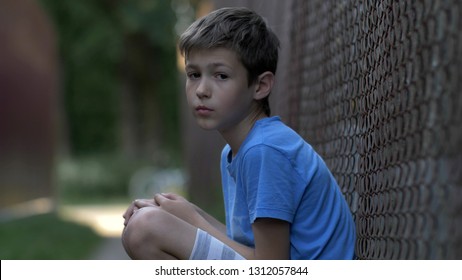 Sad upset abused teenager boy sitting alone, lonely serious offended boy, pain on face, close up