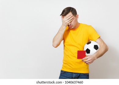 Sad Upset Crying Shocked Young Man, Football Fan Or Player In Yellow Uniform Cover Eyes By Hand, Hold Red Soccer Card For Retire From Field Isolated On White Background. Sport Play, Lifestyle Concept