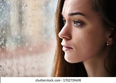 Traurige verärgerte weinende Frau mit Tränenaugen, die an emotionalem Schock, Verlust, Trauer, Lebensproblemen und einer Beziehung mit Regentropfen in der Nähe des Fensters leiden. Frauen erhielten schlechte Nachrichten