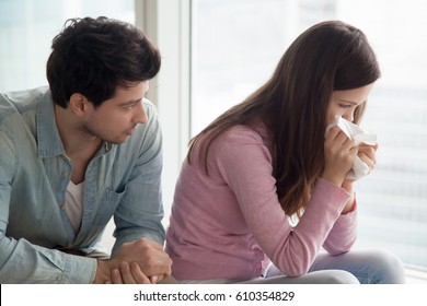 Sad upset girl crying, wiping tears with handkerchief, friend or boyfriend trying to comfort her at home, husband consoling depressed wife, support in difficult situation, compassion or apologize 