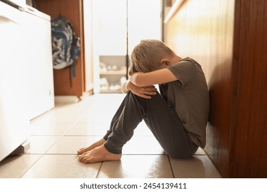 Sad upset little boy head down sitting on the floor at home 	 - Powered by Shutterstock