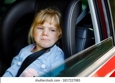 Sad Upset Little Kid Girl Sitting In Car In Traffic Jam During Going For Summer Vacation With His Parents. Tired, Exhausted Child Not Happy About Long Journey. Crying Baby.