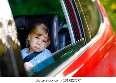 Sad Upset Little Kid Girl Sitting In Car In Traffic Jam During Going For Summer Vacation With His Parents. Tired, Exhausted Child Not Happy About Long Journey. Crying Baby.