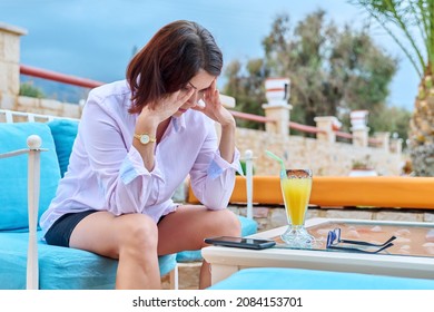 Sad Upset Mature Woman Sitting Outdoors At Table In Cafe With Smartphone