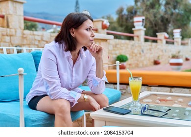 Sad Upset Mature Woman Sitting Outdoors At Table In Cafe With Smartphone