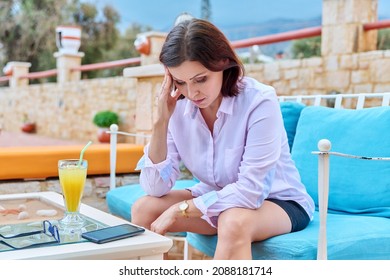 Sad Upset Mature Woman Sitting Outdoors At Table In Cafe With Smartphone