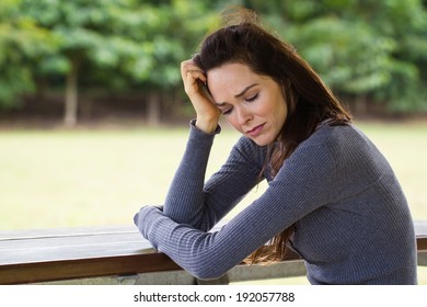 A Sad And Upset Woman Sitting Down Alone Outdoors