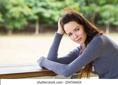 A Sad, Upset  And Worried Woman Sitting Down Alone Outdoors