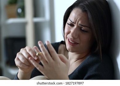Sad wife complaining and crying touching wedding ring thinking in divorce at home in the night