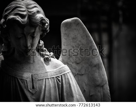 A sad winged angel at an old cemetery. Photo is in black and white with blurry effect