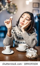 Sad Woman In A Cafe Looking Dreamily To A Piece Of White Sugar For Her Coffee. Say No To Sugar And Fast Carbs. Diet For Diabetes And Addiction To Sweet Junk Food Concept