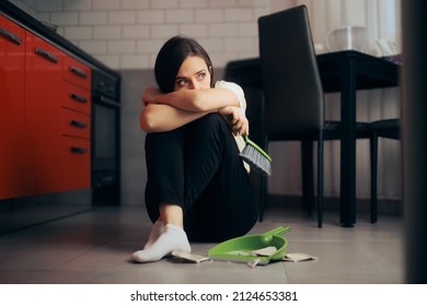 Sad Woman Crying And Cleaning Shards Of Broken Plates. Scared Victim Of Domestic Abuse Picking Up The Mess After A Fight