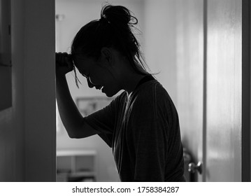 A sad woman crying and depressed in her room at home alone.