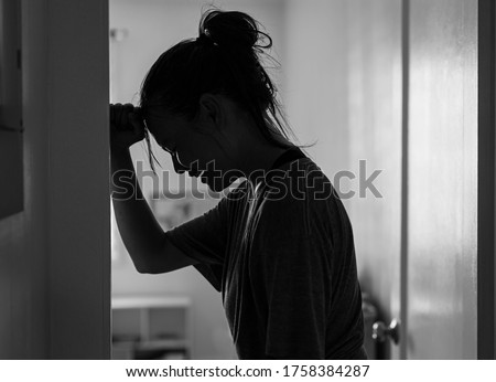 A sad woman crying and depressed in her room at home alone.