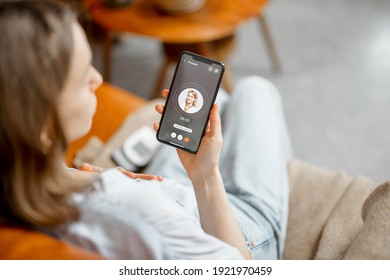 Sad woman have a high heart rate, call a doctor while sitting on sofa at home. Health and wellness concept.  - Shutterstock ID 1921970459