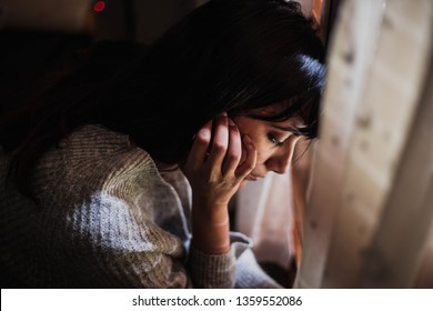 sad woman with her head down looking through the window with her eyes closed