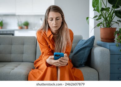 Sad woman holding mobile phone in hands, waiting for call or message. Frustrated female reading news, looking with strained uncertainty at smartphone with bad thoughts in head, loss of connection.  - Powered by Shutterstock