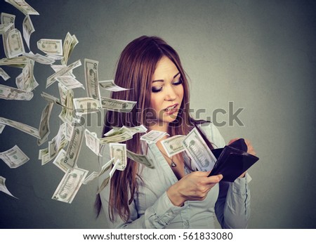 Sad woman looking at her wallet with money dollar banknotes flying out away  Foto d'archivio © 