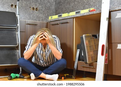 Sad Woman Makes Repairs. Bad Builder Girl At Home Repairs The Kitchen. The Housewife Fixes The Furniture Herself.