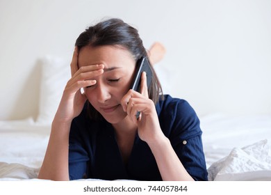 Sad Woman Making A Phone Call On The Bed