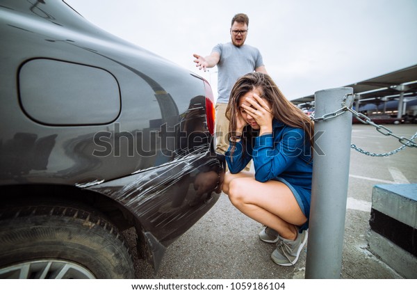 sad woman near scratched car. man shouting\
on woman. car accident. insurance\
case