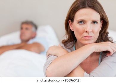 Sad Woman On The Bed With Her Husband In The Background