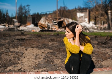 Sad Woman Owner Holds His Head By Hand Checking Burnt Out House And  Yard After Fire Disaster, Consequences Of Fire Disaster Accident. Ruins After Fire Disaster, Loss And Despair Concept.