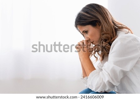 Sad woman sitting alone crestfallen looking on the floor at home