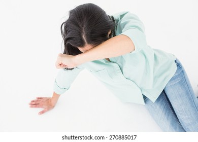 Sad woman sitting on the floor and hiding her face on white backgroung - Powered by Shutterstock