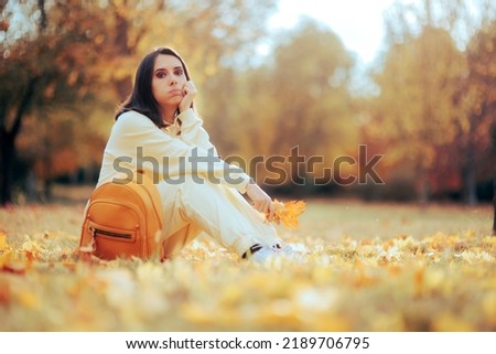 Sad Woman Sitting in the Park Resting Feeling Nostalgic. Unhappy melancholic person sitting on the ground in autumn season
