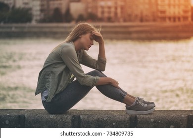 Sad woman sitting at the riverbank.Depressed woman
Image is intentionally toned.