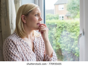 Sad Woman Suffering From Agoraphobia Looking Out Of Window