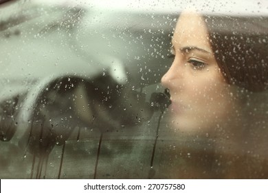 Sad woman or teenager girl looking through a steamy car window