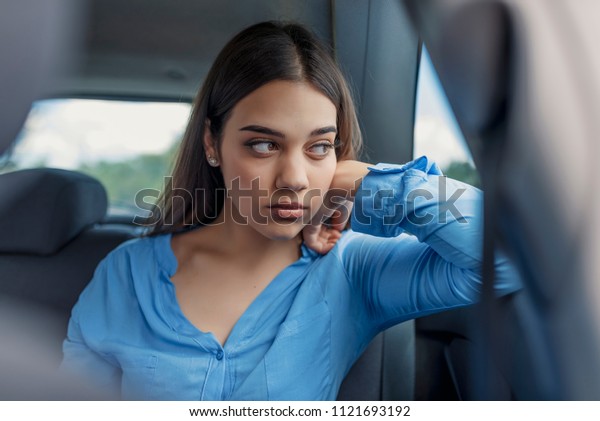 Sad woman or teenager girl looking through a car\
window. Sad woman looking down through a car window. Woman in car.\
Sullen Young Woman in a Car