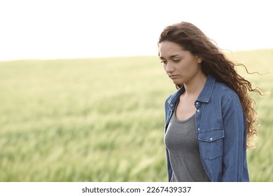 Sad woman walking alone in a wheat field - Shutterstock ID 2267439337