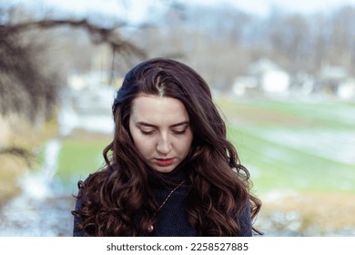 Sad woman.Girl in sadness.Portrait of a girl in nature.Beautiful curly hair.Woman looks down.Retro vintage colors.Vintage retouch.Feeling of loneliness.Winter portrait.Cold colors. Problems.Hair care. - Shutterstock ID 2258527885